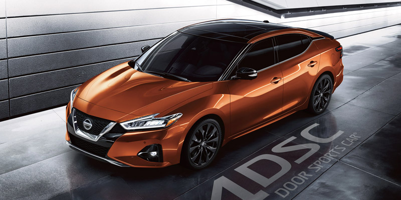 Nissan sedan with a black roof and windows sits in a garage