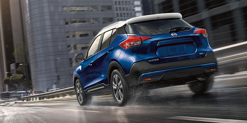 Nissan Kicks driving on a wet city street