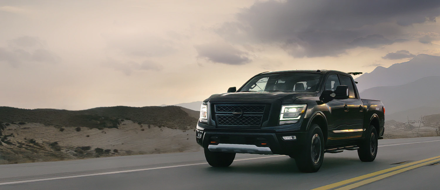 Front 3/4 view of a dark gray pickup truck driving on a highway