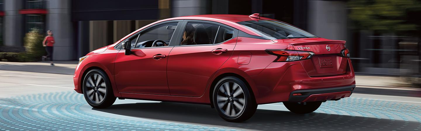 Nissan Versa drives left to right on a city street