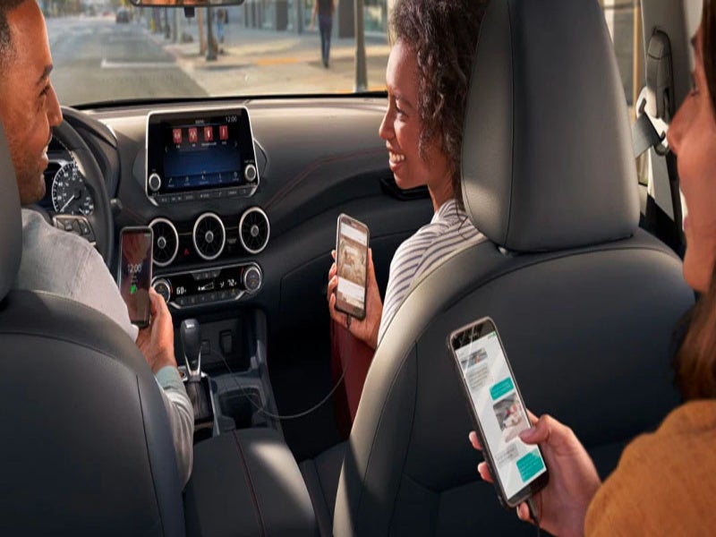 people in car using infotainment system and holding the phones